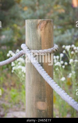 Primo piano di recinzione in corda e palo in legno nel parco pubblico Foto Stock