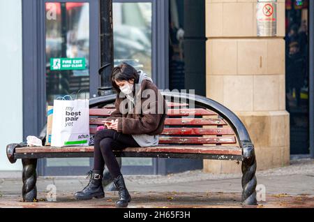 Dundee, Tayside, Scozia, Regno Unito. 13 Nov 2021. UK Meteo: Con temperature che raggiungono i 12°C nella Scozia nord-orientale, è una bella e soleggiata giornata autunnale. Questa giovane donna attraente sta inviando messaggi sul suo telefono mentre fuori shopping e godendo il tempo di autunno nel centro di Dundee città. Credit: Dundee Photographics/Alamy Live News Foto Stock