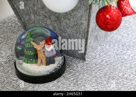 Il globo della neve di Natale con i baubles rossi colorati appesi sopra dall'albero di Natale Foto Stock