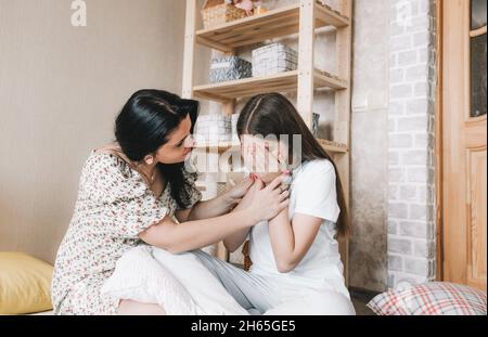 Una madre e una figlia di mezza età amorevole siedono sul pavimento, un genitore preoccupato calma un bambino con un cuore rotto, primo amore, Foto Stock