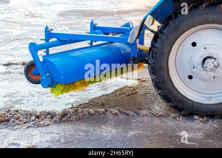 Pulizia e spazzatura delle strade dalla neve. Il trattore con la nuova spazzola incernierata libera l'area. Primo piano. Foto Stock