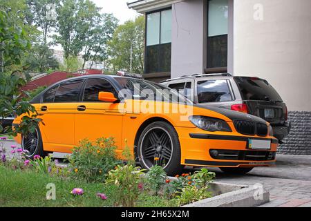 Kiev, Ucraina - 2 settembre 2017: BMW Serie 7 Alpina in un film arancione opaco sullo sfondo di altre auto e una casa Foto Stock