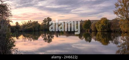 Al tramonto sul lago con riflessi all'inizio dell'autunno, vista panoramica della natura tranquilla. Nuvoloso su un bellissimo paesaggio con laghetto Foto Stock
