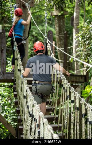 Coppia attraversando ponte sospeso baldacchino, Ecoquest Adventures & Tours, Hacienda campo Rico, Carolina, Porto Rico Foto Stock