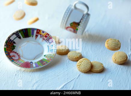 biscotti volanti, piatto e tazza di tè. Biscotti cadenti con tazza. Levitazione del cibo su sfondo bianco Foto Stock
