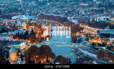 Tbilisi, Georgia. Vista dall'alto di famosi punti di riferimento nelle illuminazioni notturne. Paesaggio urbano Georgian Capital Skyline. Città durante il tramonto e luci notturne Foto Stock