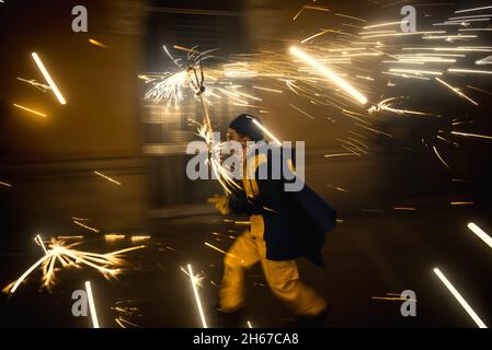 Barcellona, Spagna. 13 Nov 2021. I corridori del fuoco della 'Diabolica de Gracia' ballano a batteria tradizionale sotto i loro scintillanti fuochi d'artificio attraverso le strade del quartiere Gracia di Barcellona per celebrare il loro 39 ° anniversario di credito: Matthias Oesterle/Alamy Live News Foto Stock