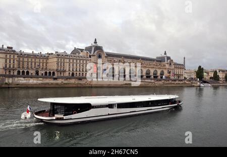 Una barca viaggia lungo la Senna a Parigi, passando per il simbolo Musée d'Orsay, un museo d'arte ospitato nella storica ex stazione ferroviaria Gare d'Orsay. Foto Stock