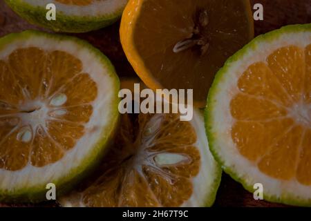 Fette fresche e succose di limone e lime su un tagliere di legno. Foto Stock