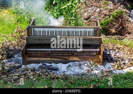 Un vecchio pianoforte di P.A. Starck si trova in un fuoco da bruciare. Foto Stock