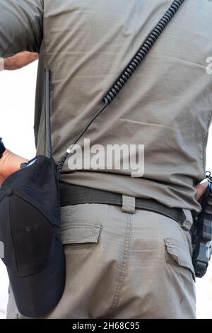 Vista posteriore del poliziotto del coperchio inferiore avvisato o dell'agente di sicurezza che raggiunge la pistola a mano fissata al nastro. Ritratto a tutta lunghezza isolato su sfondo bianco studio. . Foto di alta qualità Foto Stock