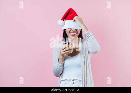 donna di natale ispanica, con una tazza di argilla di caffè o punch di frutta su sfondo rosa in america latina Foto Stock