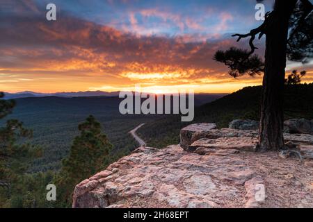 Arizona tramonto, dalla cima del Mogollan Rim sopra Payson. Pineta e autostrada sottostante; Sunburst, brillanti nuvole d'arancio e cielo blu in lontananza. Foto Stock