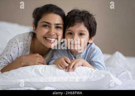 Felice mamma indiana e bambino sdraiato in lino bianco Foto Stock