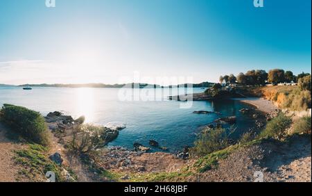 Vouliagmeni Beach vicino ad Atene in Grecia, Europa. Idilliaca baia panoramica durante il tramonto. Foto Stock