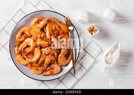 Gamberi al burro all'aglio alla griglia, Gambas al Ajillo spagnolo su un piatto su un tavolo di legno bianco, piatto Foto Stock
