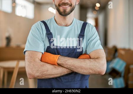 Uomo allegro in guanti di tenuta braccia incrociate Foto Stock