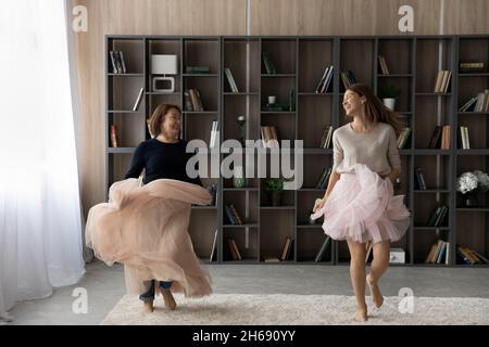 Donna felice con madre matura che indossa gonne rosa ballando insieme Foto Stock