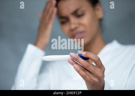 Infelice frustrato giovane etnia africana che tiene il test di gravidanza. Foto Stock