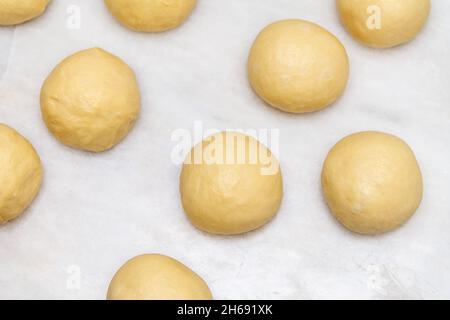 Vista dall'alto delle palle di pasta cruda realizzate per la cottura di dolci su marmo bianco Foto Stock