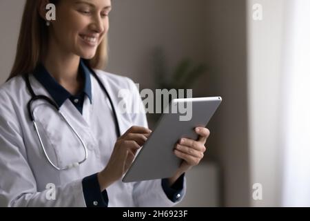 Primo piano sorridente giovane donna medico in uniforme usando la compressa Foto Stock