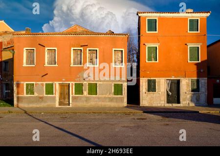 Molte finestre in due vecchie case arancioni con persiane chiuse, isola di Pellestrina, laguna veneta, Italia Foto Stock