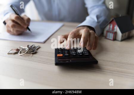 Primo piano giovane uomo con calcolatore, pianificazione degli investimenti immobiliari. Foto Stock