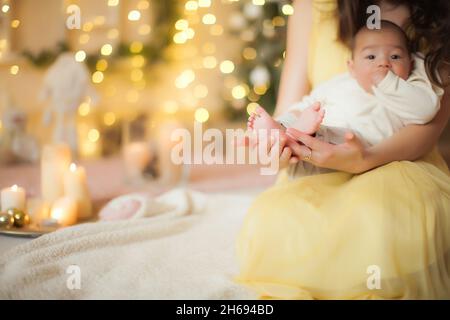 Una giovane madre alla vigilia di Capodanno tiene un bambino tra le braccia. Foto Stock