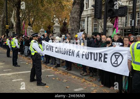 Londra, Regno Unito. 13 Nov 2021. Estinzione gli attivisti del clima della ribellione hanno tenuto una bandiera di Give Children un futuro durante un aumento e la marcia di Rebel organizzata per coincidere con la fine e il fallimento previsto del vertice sul clima della COP26. Gli attivisti intendevano inviare un messaggio al governo del Regno Unito secondo cui le proteste per garantire un'azione urgente per affrontare l'emergenza climatica ed ecologica continueranno. La marcia ha interrotto brevemente lo spettacolo del Signore Sindaco in due o più luoghi. Credit: Mark Kerrison/Alamy Live News Foto Stock