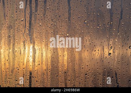 Gocce di pioggia o di rugiada che scorrono lungo il bicchiere sullo sfondo di una splendida alba o tramonto Foto Stock
