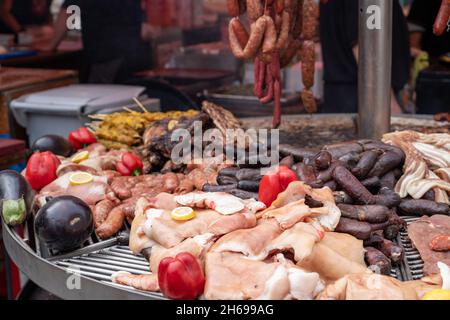 Una grande griglia con diverse carni, salsicce e verdure su un fuoco aperto all'aria aperta in una festa della città dedicata al Medioevo Foto Stock