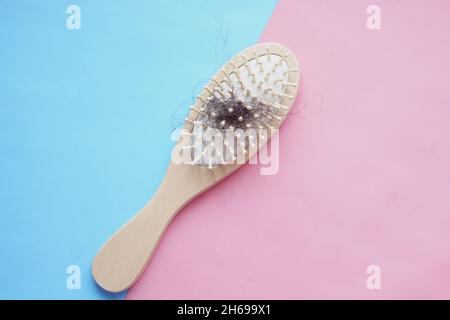 una spazzola con capelli persi su sfondo rosa Foto Stock