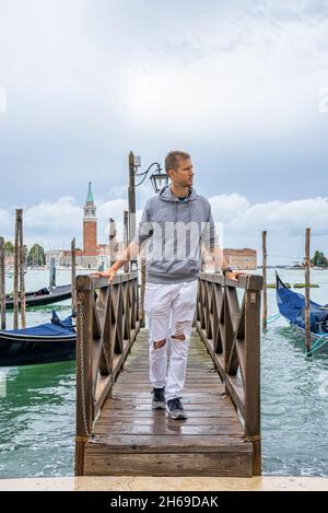 Uomo in piedi sul molo sul mare e ammirare la natura panoramica Foto Stock