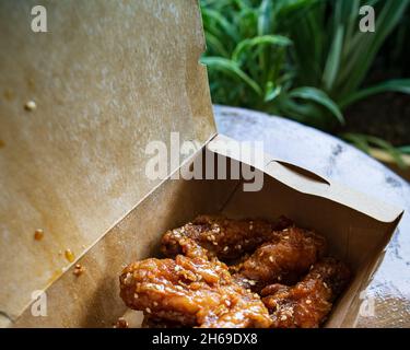 Ali di pollo fritto coreano e drummets in una scatola da portare via. Ricetta tradizionale asiatica. Foto Stock