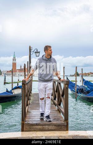 Uomo in piedi sul molo sul mare e ammirare la natura panoramica Foto Stock