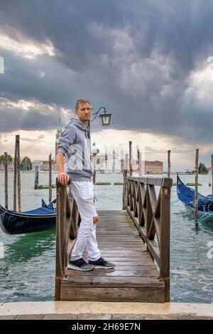 Uomo in piedi sul molo sul mare e ammirare la natura panoramica Foto Stock