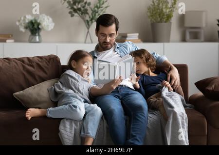 Il padre che si prende cura di leggere il libro a figliuola e figlio Foto Stock