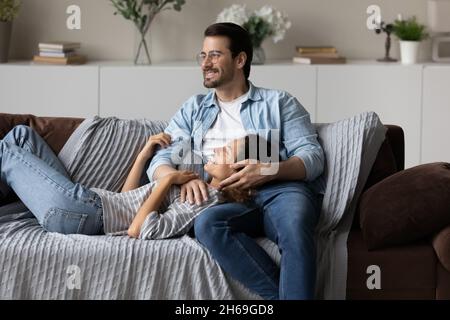 Coppia allegra e sognante che si rilassa sul divano, guardando in lontananza insieme Foto Stock