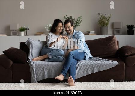 Felice coppia giovane che si diverte con lo smartphone a casa Foto Stock