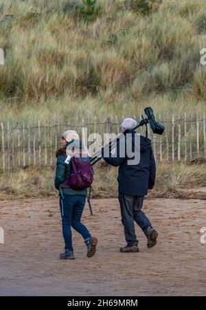 coppia di età media birdwatching o twitching sulla costa nord del norfolk, uomo che porta un ampio spazio di avvistamento per gli uccelli. Foto Stock