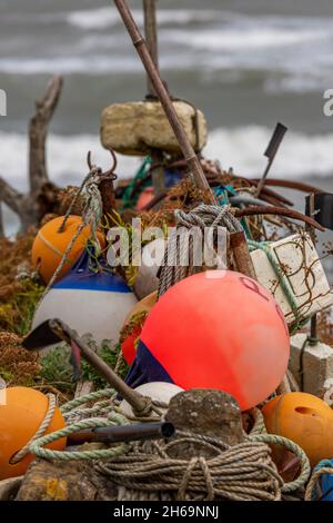 attrezzatura da pesca di pescatori scartati galleggia e galline, danbuoy e galleggia attrezzi da pesca immagazzinati su un molo, jumble o kit di pesca aggrovigliato sul porto. Foto Stock