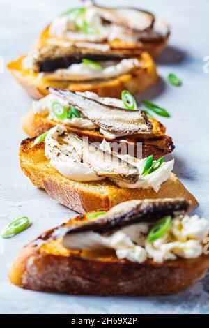 Toast con formaggio cremoso, spratti di pesce e cipolle verdi. Semplice concetto di ricette fatte in casa. Foto Stock