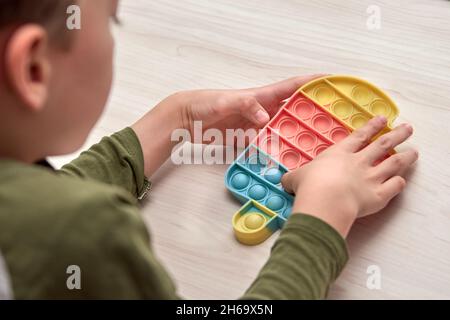 Le mani dei capretti spingono il schiocco sensoriale esso. Giocattoli antistress colorati, dimple semplice, tubo pop. Rainbow silicone sensoriale Fidget nuovo popolare giocattolo in silicone alla moda. Foto Stock