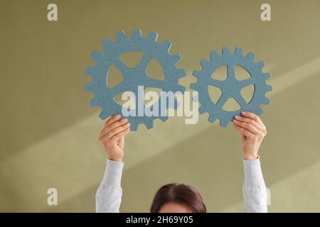 Donna che collega due ruote dentate illustrando il concetto di innovazione e integrazione Foto Stock