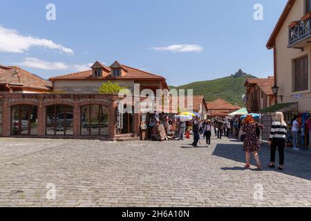 Mtskheta, Georgia - 28 aprile 2019: I turisti camminano per la strada della città vecchia di Mtskheta. Il monastero di Jvari è sullo sfondo della cima della montagna Foto Stock