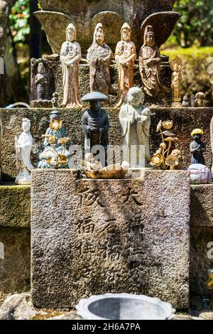 Statue di Gizo e di kannon buddista sotto un piedistallo di loto di pietra al tempio di Daiganji, Kikyozan Hokoin, sull'isola di Miyajima in Giappone. Foto Stock
