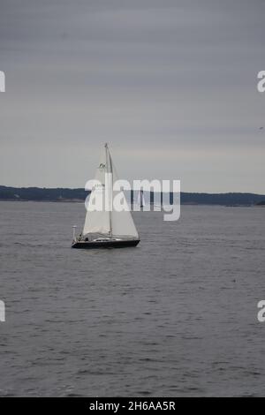 barca a vela con vele completamente aperte in una giornata nuvolosa di colore grigio nel porto Foto Stock