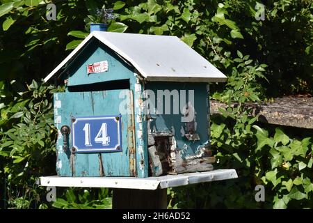 Una mailbox fatta in casa, una scatola in legno color turchese a forma di casa con tetto a falde e l'intera apertura frontale su cerniera a piano Foto Stock