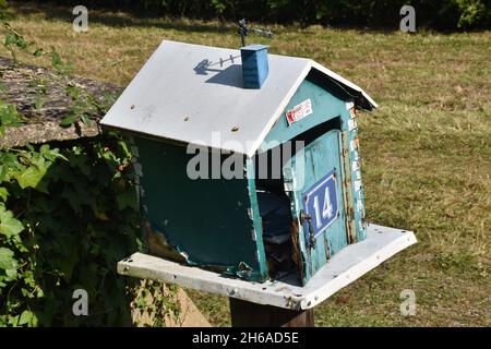 Una mailbox fatta in casa, una scatola in legno color turchese a forma di casa con tetto a falde e l'intera apertura frontale su cerniera a piano Foto Stock