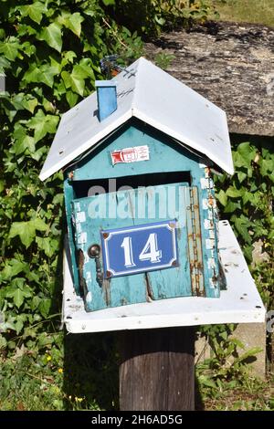 Una mailbox fatta in casa, una scatola in legno color turchese a forma di casa con tetto a falde e l'intera apertura frontale su cerniera a piano Foto Stock